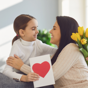 enfant qui offre une carte avec un coeur à sa maman pour la fête des mères